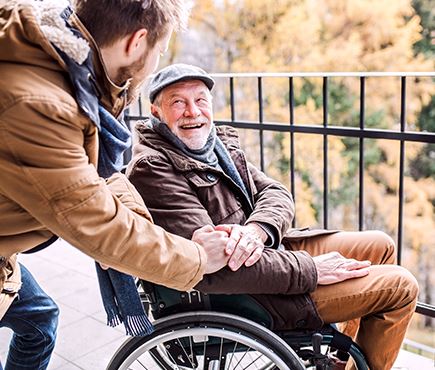 senior citizen in a wheel chair greeting young man